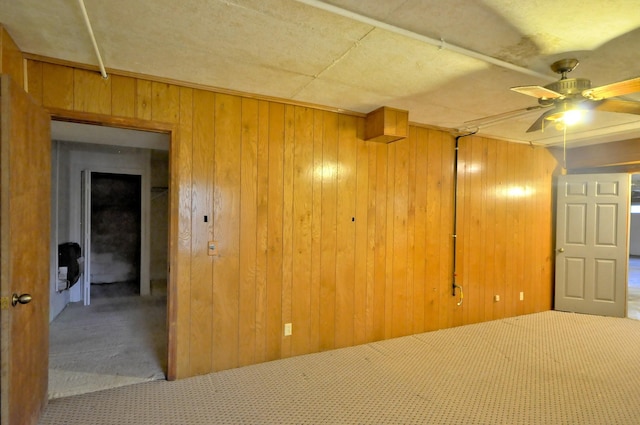 empty room with wood walls, carpet, and a ceiling fan