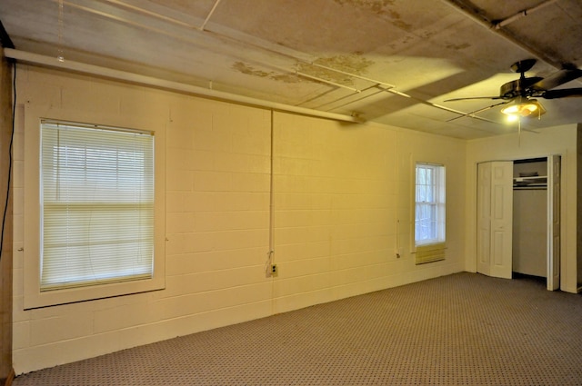 interior space featuring a closet, concrete block wall, and a ceiling fan