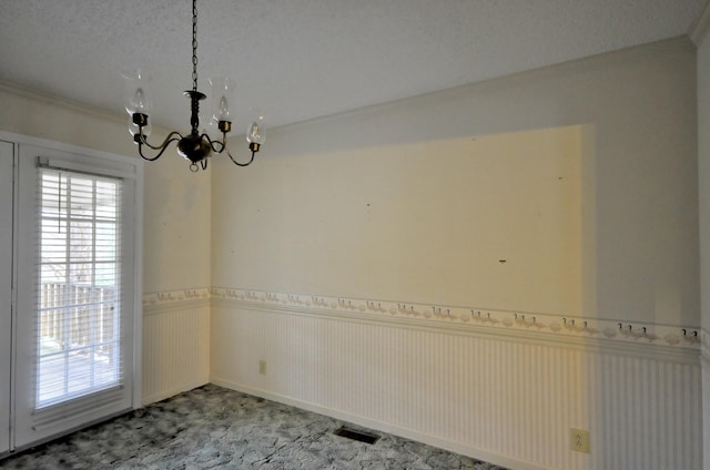 empty room with a textured ceiling, visible vents, ornamental molding, wainscoting, and an inviting chandelier