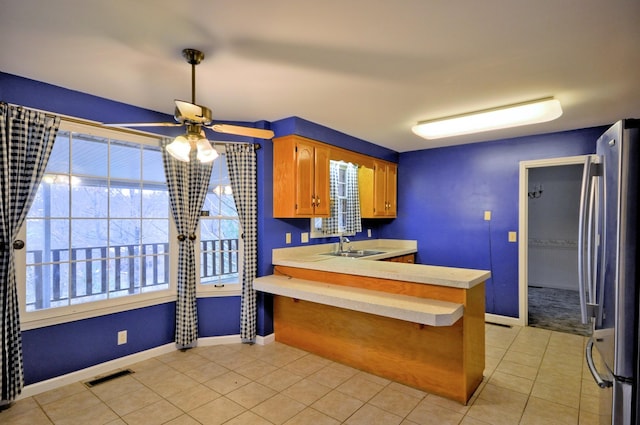 kitchen with visible vents, light countertops, light tile patterned flooring, and freestanding refrigerator