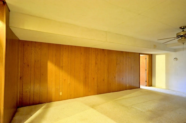 carpeted spare room with a ceiling fan and wooden walls