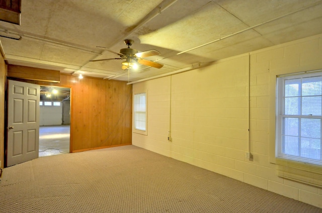 unfurnished room featuring concrete block wall and a ceiling fan