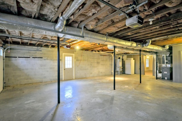 basement featuring water heater, freestanding refrigerator, and heating unit