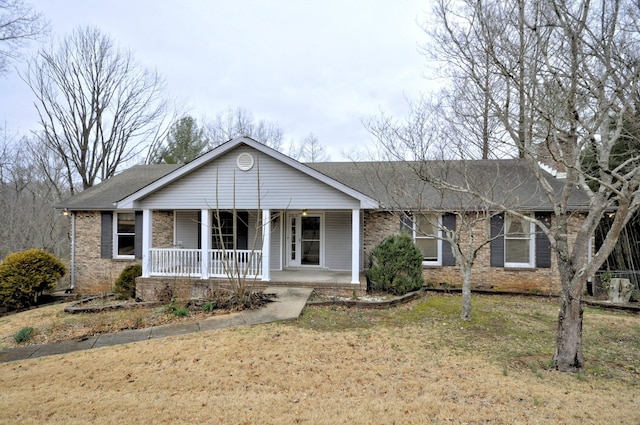 single story home featuring covered porch, a front lawn, and brick siding