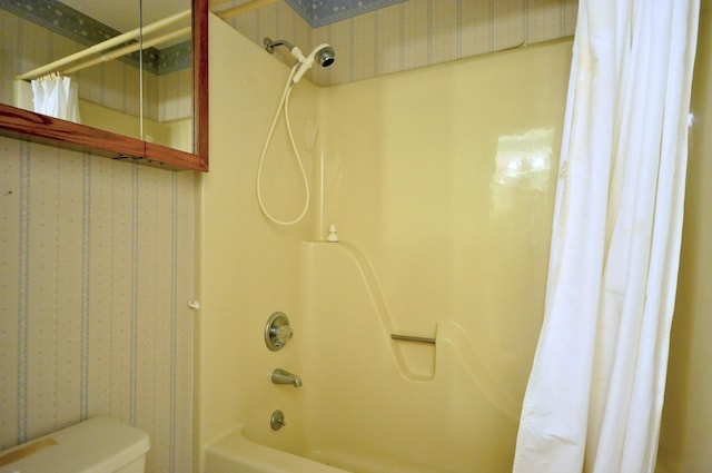 bathroom featuring toilet, shower / tub combo, and wallpapered walls