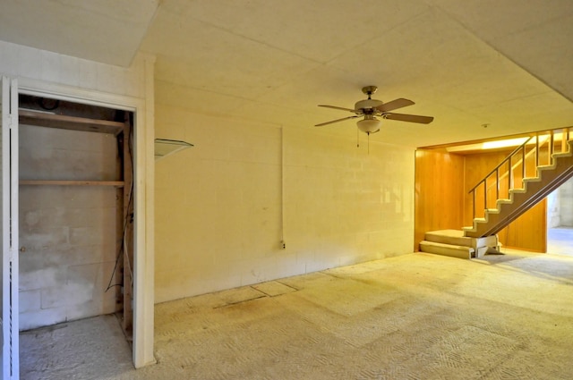 below grade area with a ceiling fan, concrete block wall, and stairs