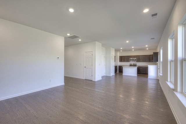 unfurnished living room featuring dark wood-style floors, baseboards, visible vents, and recessed lighting