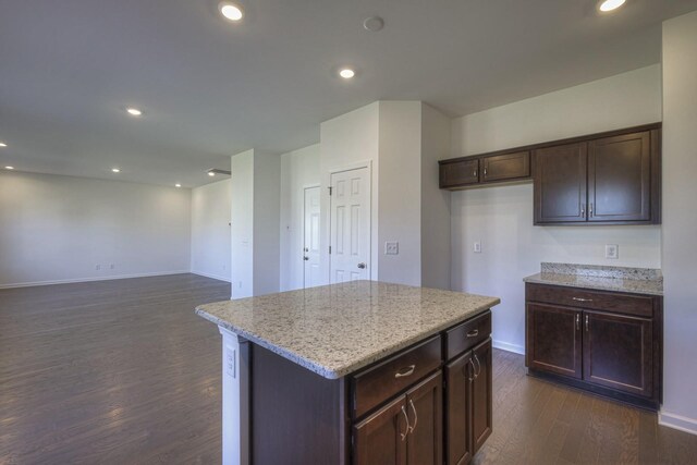 kitchen with dark wood-type flooring, recessed lighting, a center island, and light stone counters