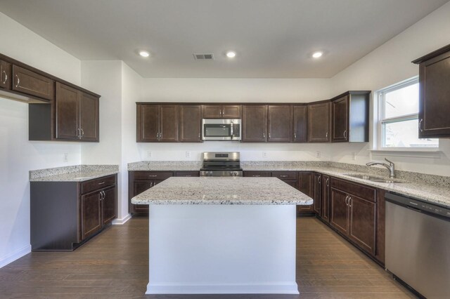 kitchen featuring appliances with stainless steel finishes, visible vents, a sink, and dark brown cabinets