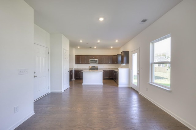 kitchen with a center island, dark wood finished floors, stainless steel appliances, dark brown cabinetry, and baseboards