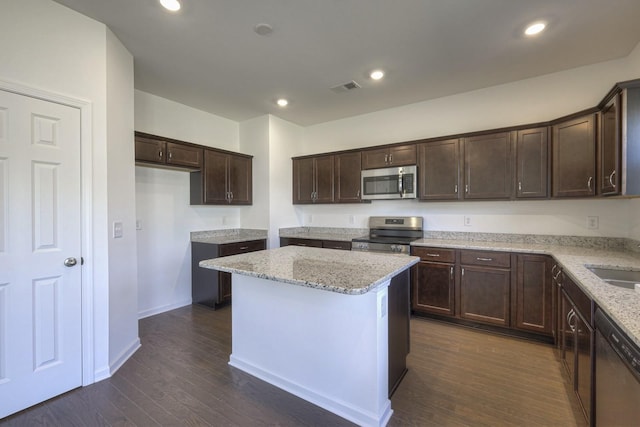 kitchen with dark brown cabinetry, stainless steel appliances, dark wood-type flooring, a kitchen island, and visible vents