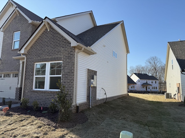 view of side of home with brick siding, a yard, and central AC