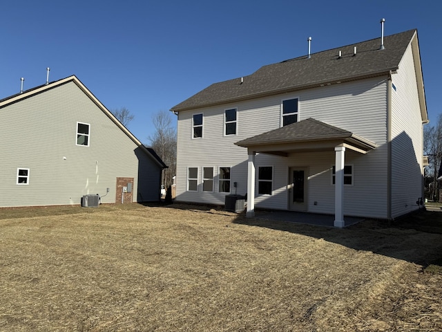 rear view of house featuring central AC and roof with shingles