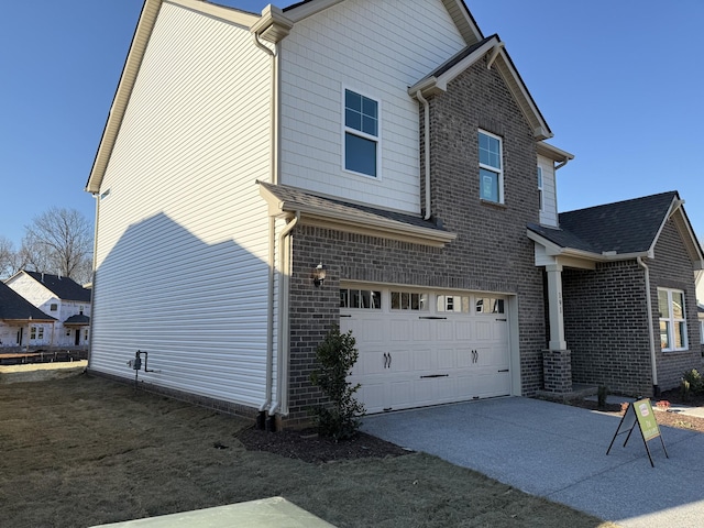 view of side of home with a garage, driveway, and brick siding