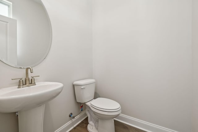 bathroom featuring a sink, toilet, baseboards, and wood finished floors