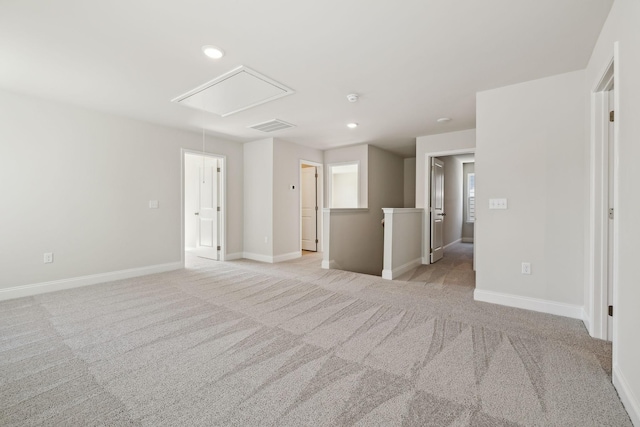 unfurnished room featuring attic access, visible vents, baseboards, and light colored carpet