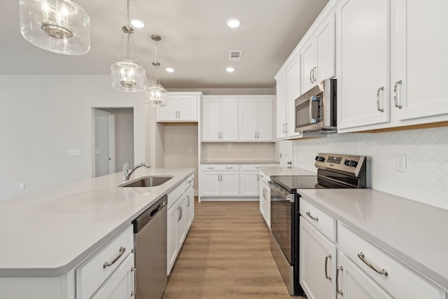 kitchen featuring stainless steel appliances, a sink, white cabinets, light countertops, and light wood-type flooring