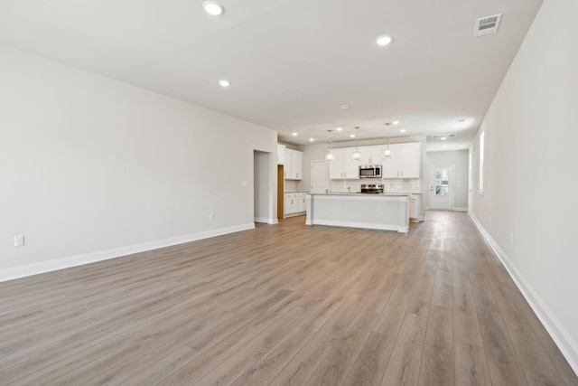 unfurnished living room with baseboards, light wood-style flooring, visible vents, and recessed lighting