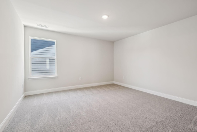 carpeted spare room with visible vents and baseboards