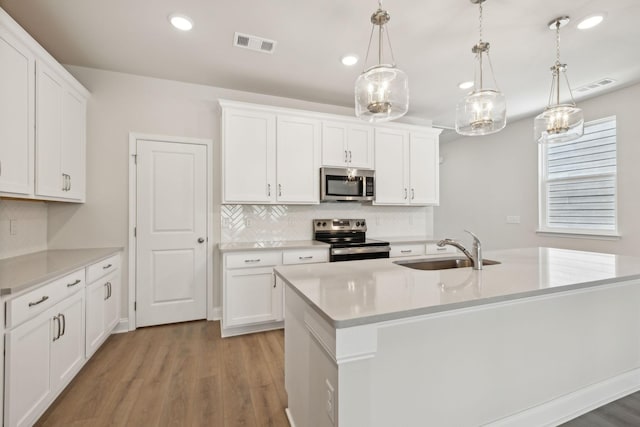 kitchen with appliances with stainless steel finishes, light countertops, visible vents, and a sink