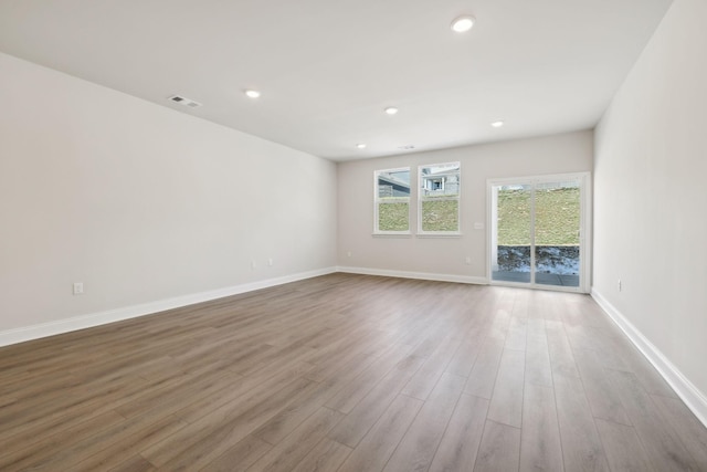 spare room featuring recessed lighting, wood finished floors, visible vents, and baseboards