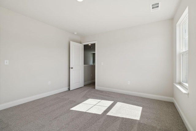 carpeted empty room featuring baseboards and visible vents