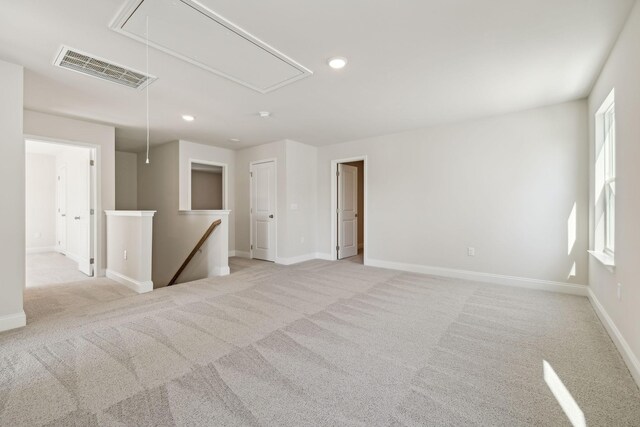 empty room with carpet floors, recessed lighting, visible vents, attic access, and baseboards