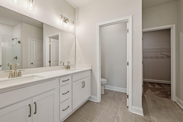 bathroom featuring a stall shower, a sink, toilet, and a walk in closet