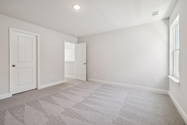 unfurnished bedroom featuring visible vents, light carpet, and baseboards