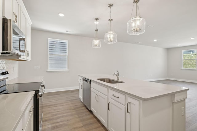 kitchen featuring stainless steel appliances, light countertops, light wood-style flooring, white cabinets, and a sink