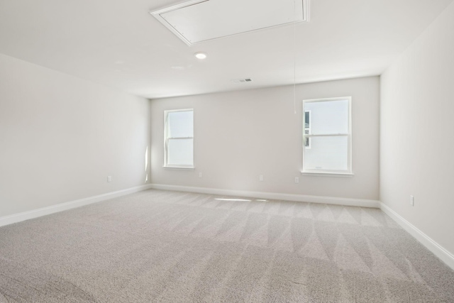 spare room featuring attic access, visible vents, baseboards, and light colored carpet