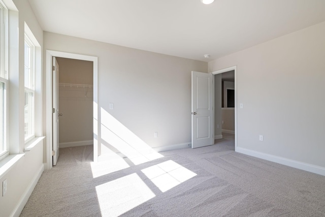 spare room featuring a healthy amount of sunlight, baseboards, and light colored carpet