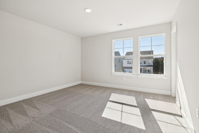 unfurnished room with carpet floors, visible vents, and baseboards