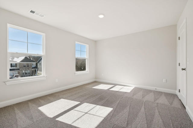 unfurnished room with carpet flooring, visible vents, and baseboards