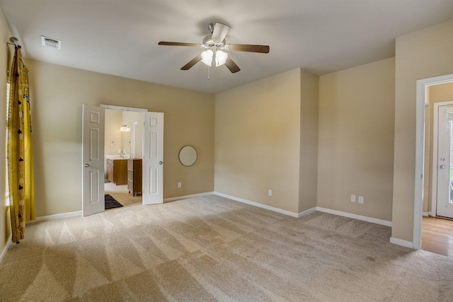 unfurnished bedroom featuring visible vents, light carpet, baseboards, and ensuite bathroom