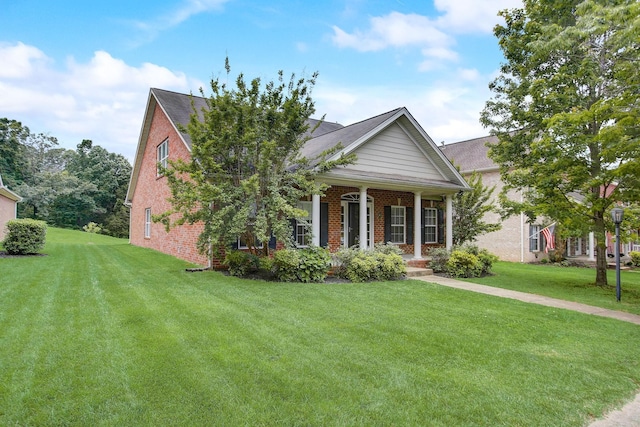 neoclassical home with covered porch, brick siding, and a front yard