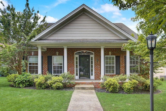 view of front facade featuring a front yard, a porch, and brick siding