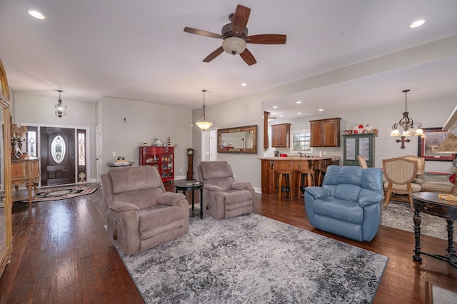 living room with ceiling fan with notable chandelier, dark wood finished floors, and recessed lighting