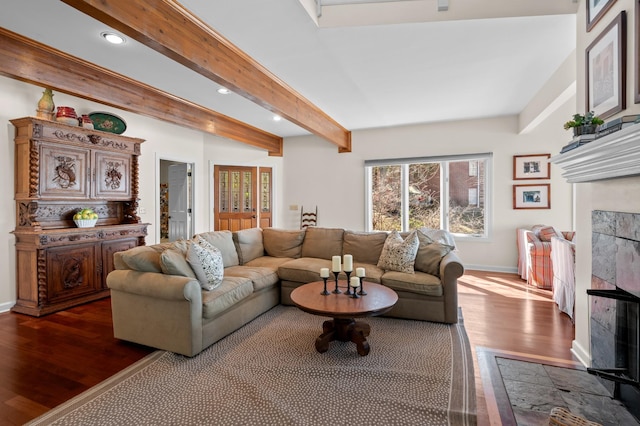 living area with baseboards, a tiled fireplace, beamed ceiling, wood finished floors, and recessed lighting