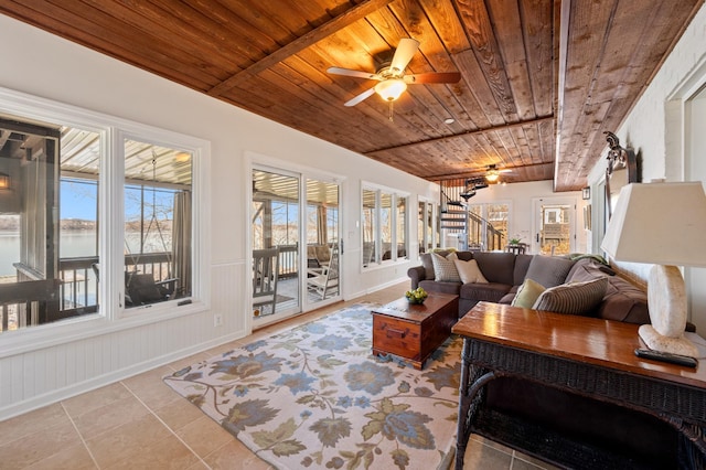 living area with light tile patterned floors, stairway, a ceiling fan, wainscoting, and wooden ceiling