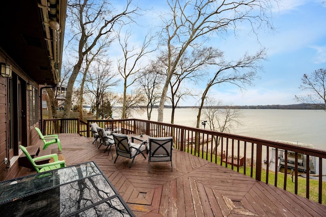 deck with outdoor dining space and a water view