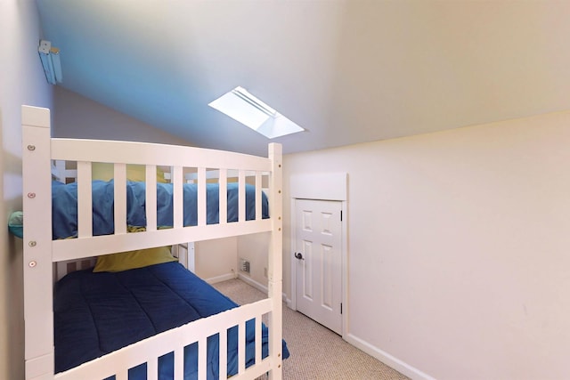 carpeted bedroom with vaulted ceiling with skylight and baseboards