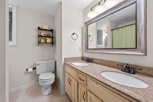 full bathroom with toilet, double vanity, a sink, and tile patterned floors