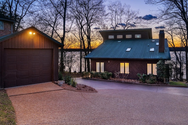 view of front of house featuring an outbuilding, metal roof, driveway, and a chimney