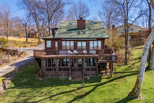 rear view of property with a chimney, a yard, a deck, and metal roof