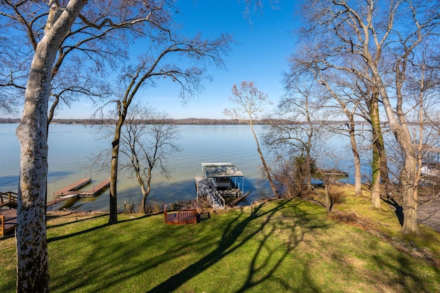 exterior space featuring a water view, boat lift, and a lawn