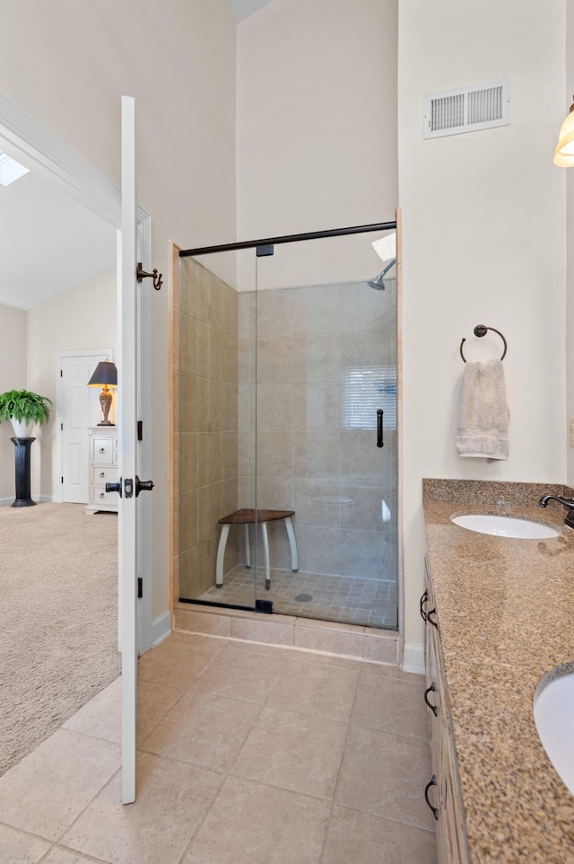 bathroom with a sink, visible vents, a shower stall, tile patterned floors, and double vanity