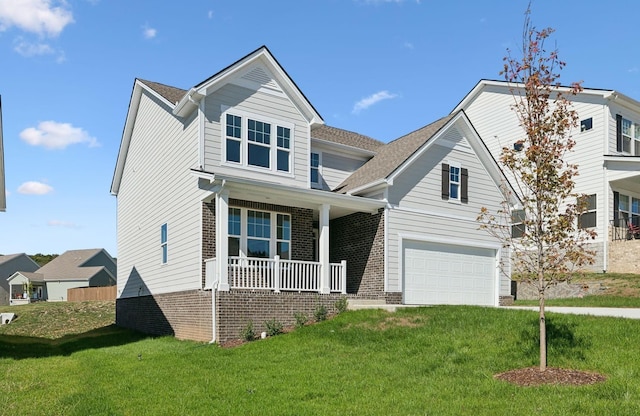 view of front facade featuring a garage, a front yard, covered porch, and brick siding