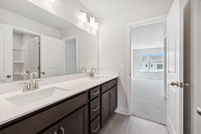 full bathroom with baseboards, double vanity, a sink, and tile patterned floors