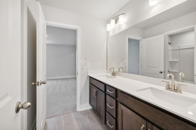 bathroom with double vanity, a sink, and baseboards